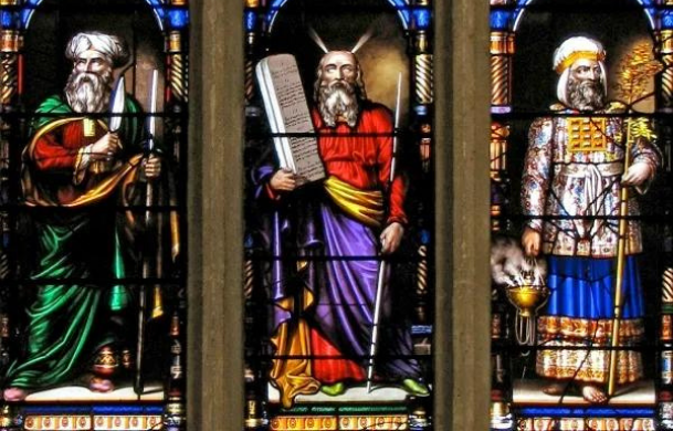 A stained glass window depicting a prophet, a priest, and a king.